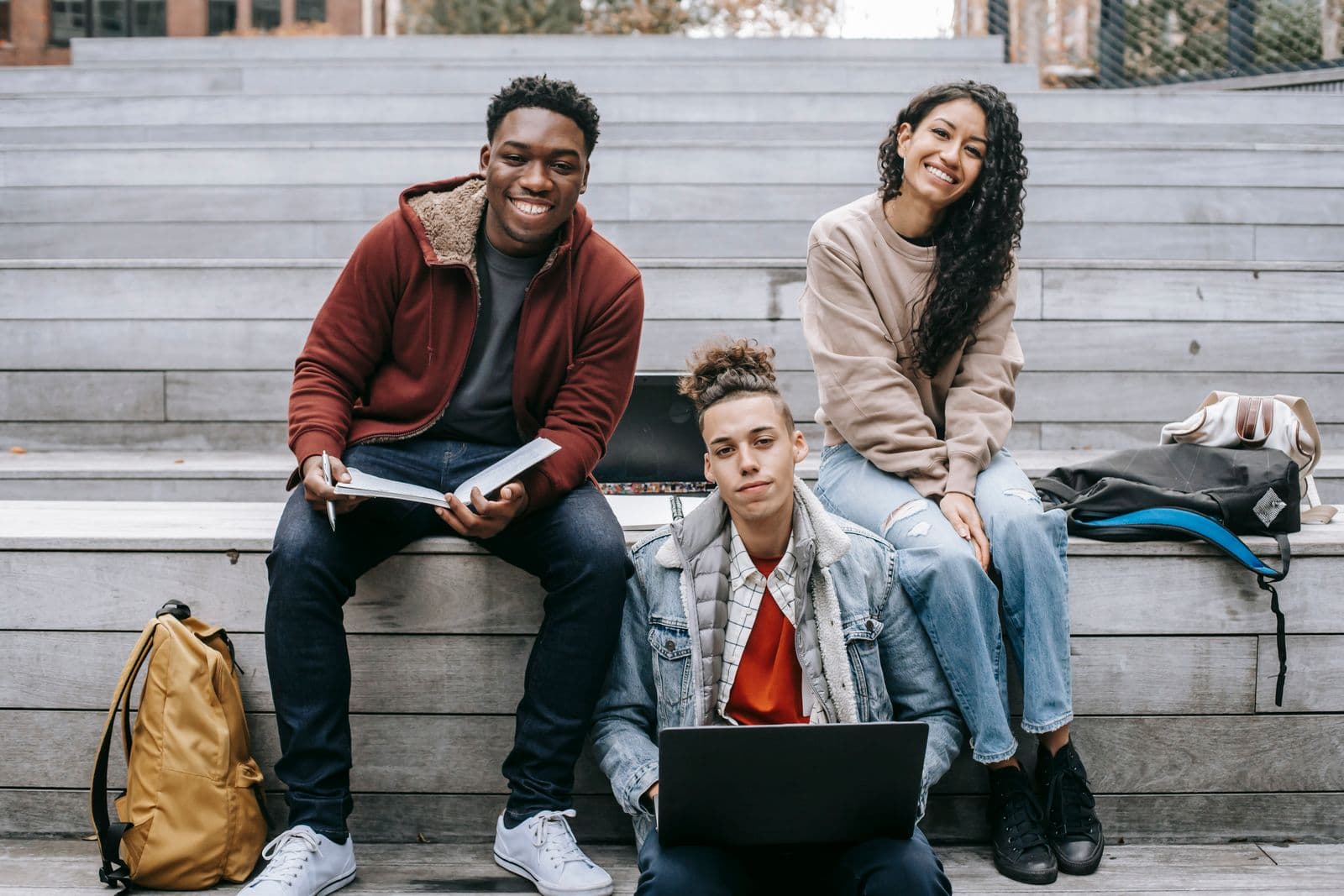 Groupe d'étudiants souriants, ordinateur portable et sacs à dos